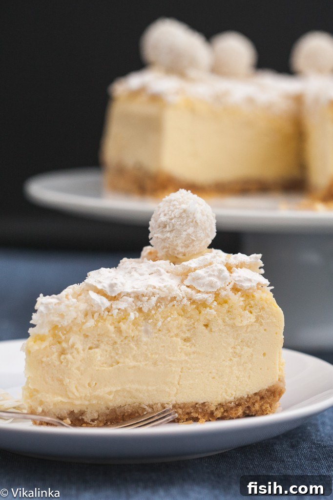 A perfectly portioned slice of Raffaello cheesecake on a plate, with the rest of the cake visible in the background, showing its beautiful layers and texture.