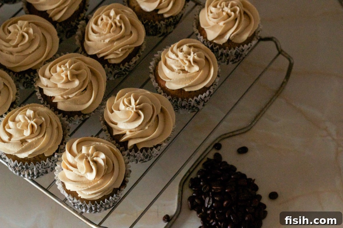 A batch of freshly baked pumpkin spice latte cupcakes resting on a wire cooling rack, awaiting their luscious frosting and final decorative touches.