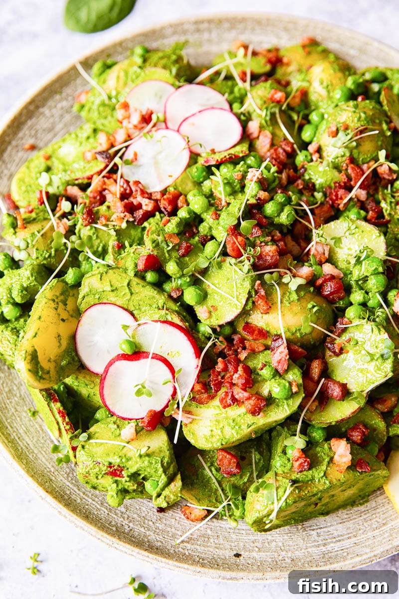 Vibrant Pesto Potato Salad with radishes, peas, and crispy bacon bits, served in a large, rustic bowl for a gathering.