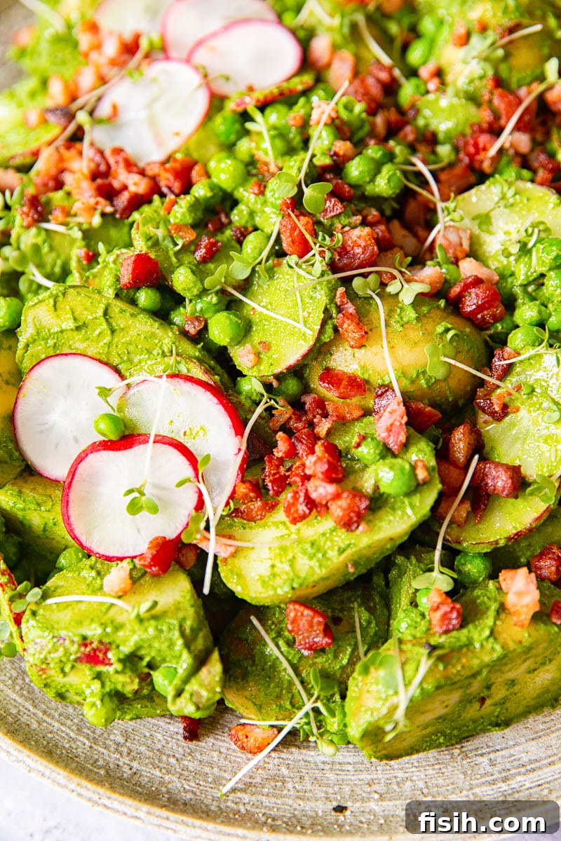 Pesto Potato Salad elegantly garnished with fresh sliced radishes and perfectly crispy bacon bits, arranged for serving.