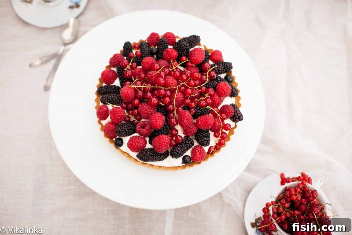 Top down shot of a beautifully arranged Summer Berry Tart on a pristine white platter, highlighting its artistry.
