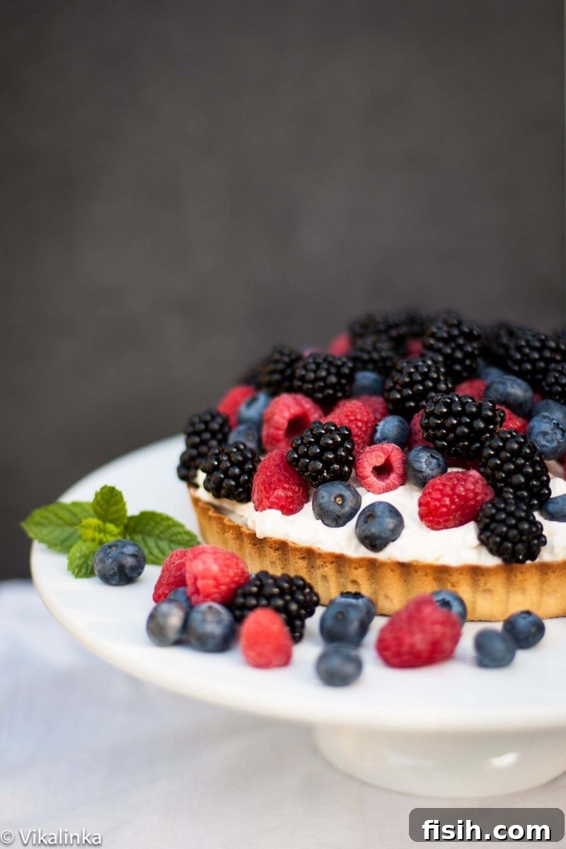 Side shot of the finished Summer Berry Tart, brimming with blueberries, blackberries, and raspberries, looking delectable.