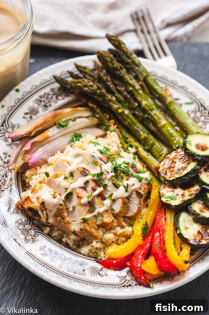 Moroccan Chicken and Roasted Veggie Couscous Bowl 7 Mediterranean couscous bowl in a small dish, showing a colorful spread of ingredients including Moroccan chicken, roasted vegetables, and couscous