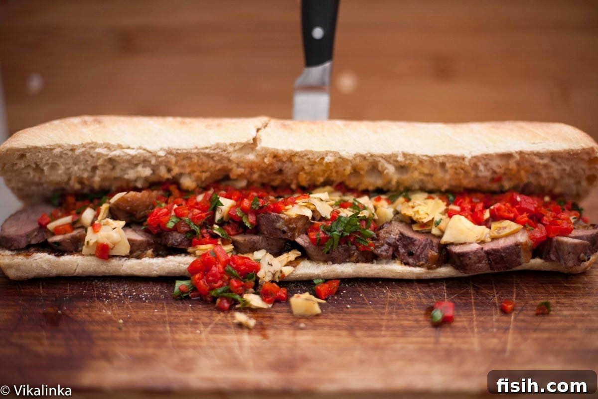 Close up of duck breast sandwich with knife in background, highlighting crispy skin and fresh toppings.