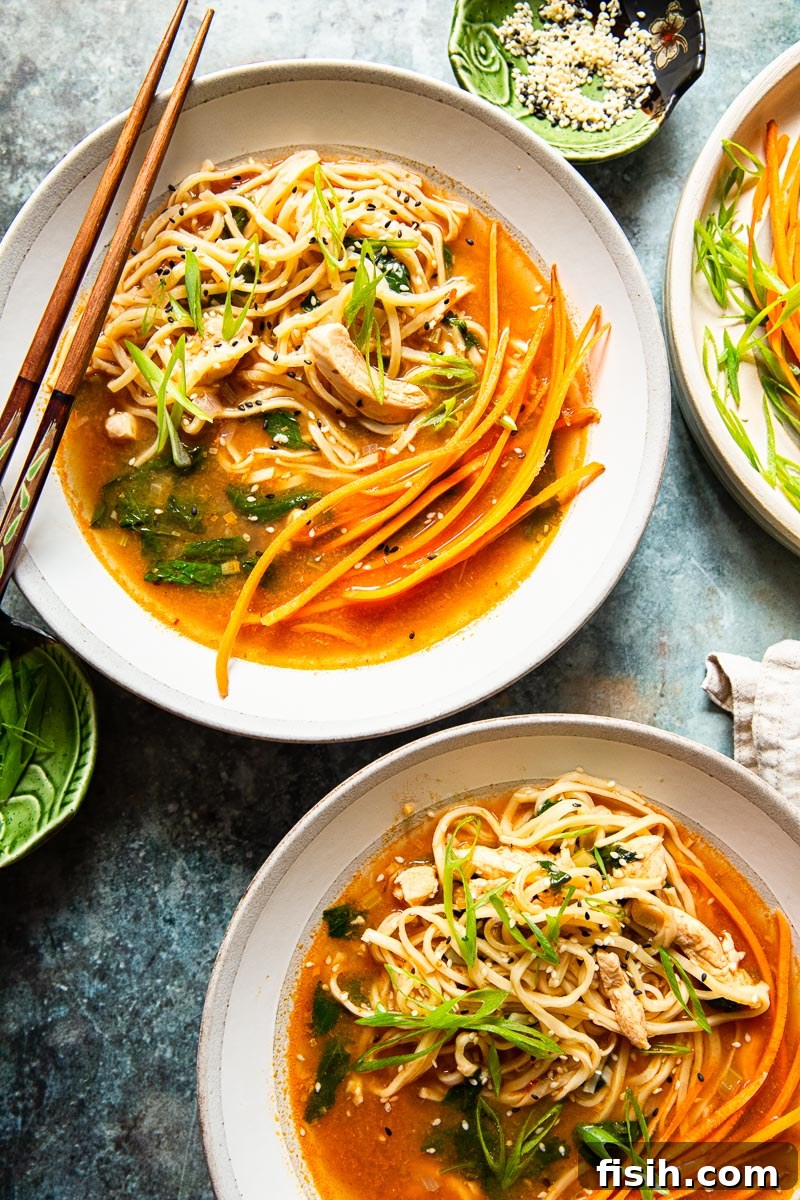 Authentic Thai Noodle Soup Made Easy 3 Top-down view of two steaming bowls of authentic Thai Chicken Noodle Soup, garnished and ready to serve.