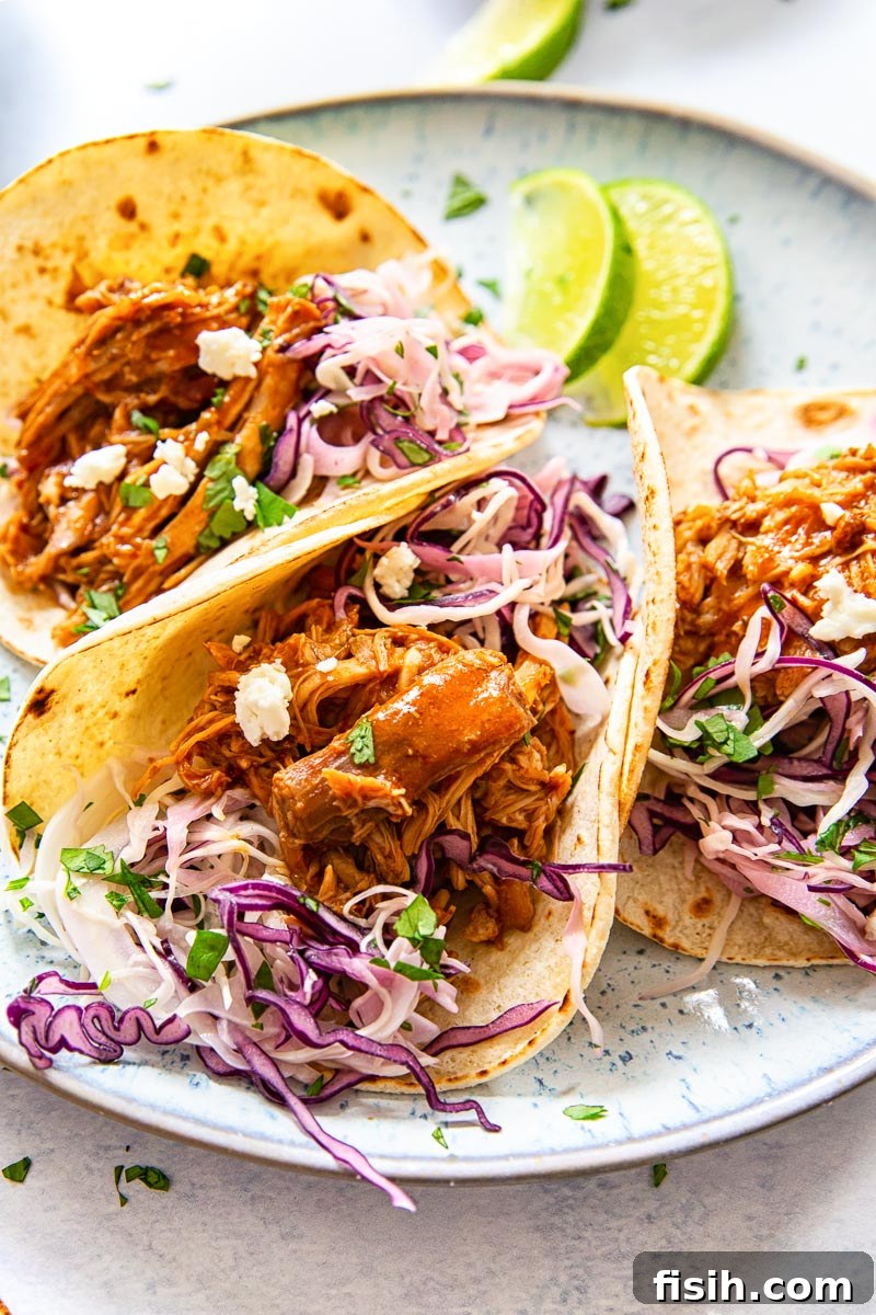 Melt-in-Your-Mouth Pulled Pork Tacos with Bright Cilantro Lime Slaw 2 3 pork tacos with slaw on blue plate