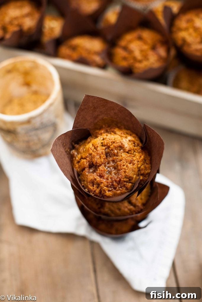 Golden Pumpkin Muffins with Toffee Honeycomb Crunch 4 A delectable stack of three toffee honeycomb pumpkin muffins, with more muffins blurred in the background, highlighting their inviting texture.