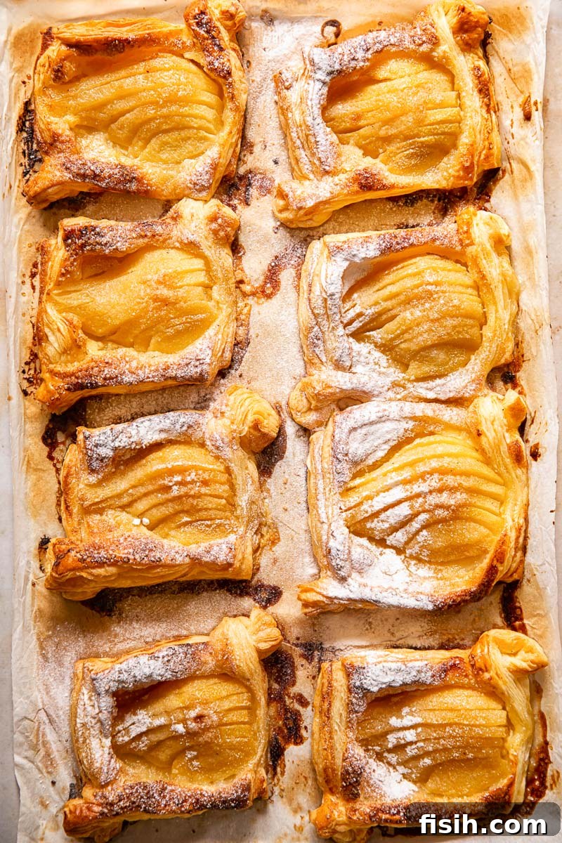 pear tarts dusted with powdered sugar on a baking tray