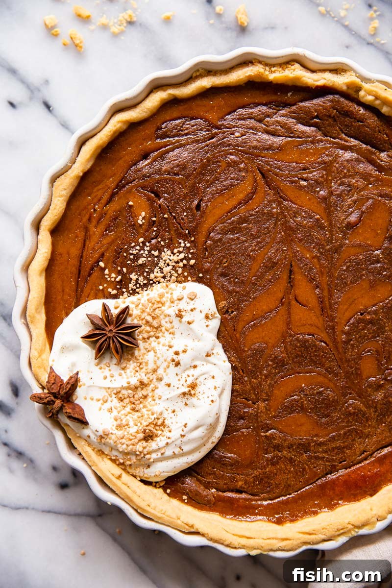 A beautifully sliced pumpkin pie featuring a distinctive chocolate swirl, topped generously with fluffy whipped cream, ready to be enjoyed.