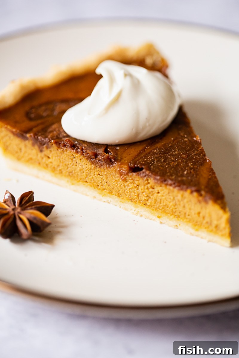 A perfect slice of pumpkin pie, elegantly presented with a dollop of whipped cream on top, showcasing the smooth texture and rich color of the filling.
