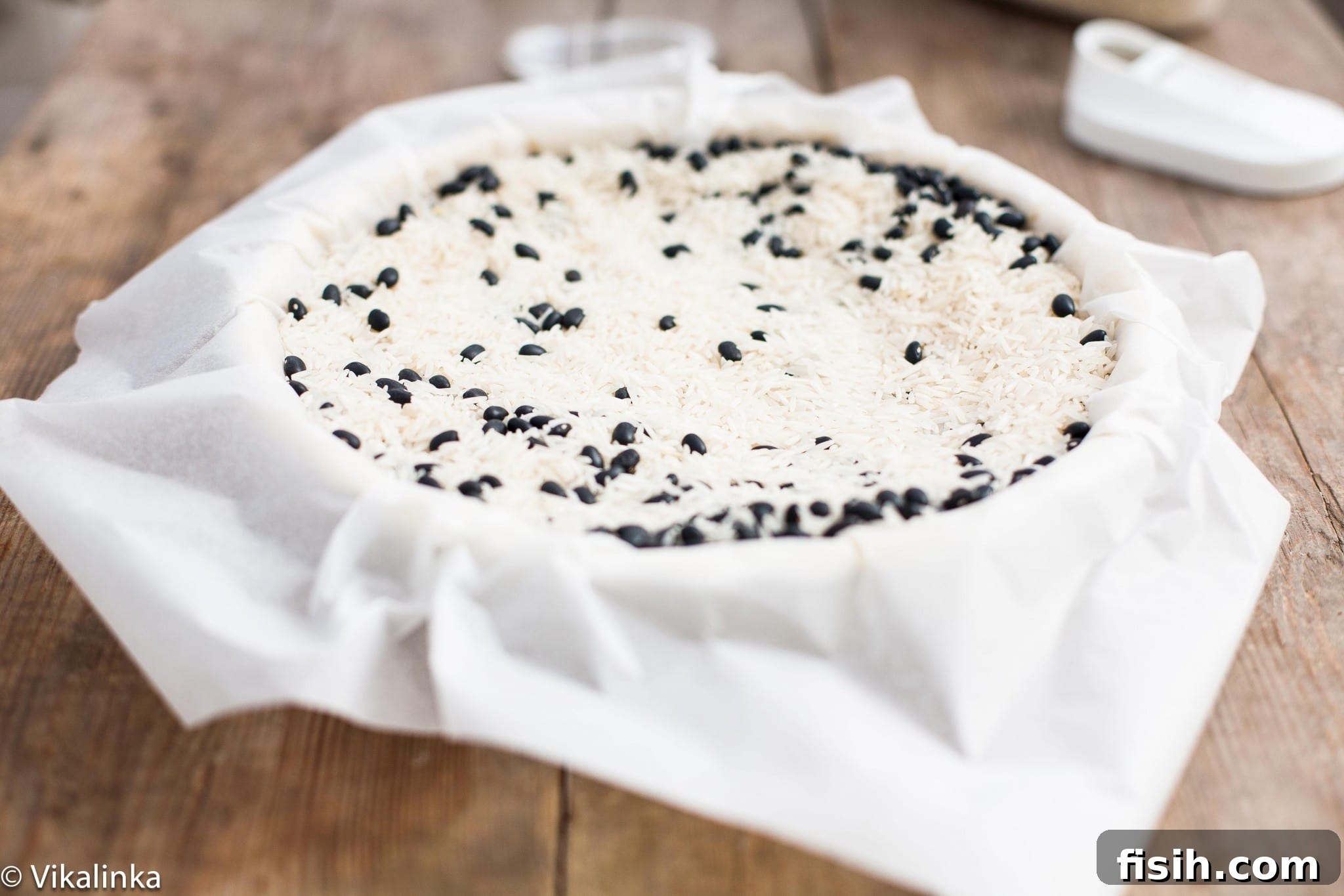A pie crust being prepared for blind baking, with parchment paper and weights placed inside, demonstrating an important step in pie making.