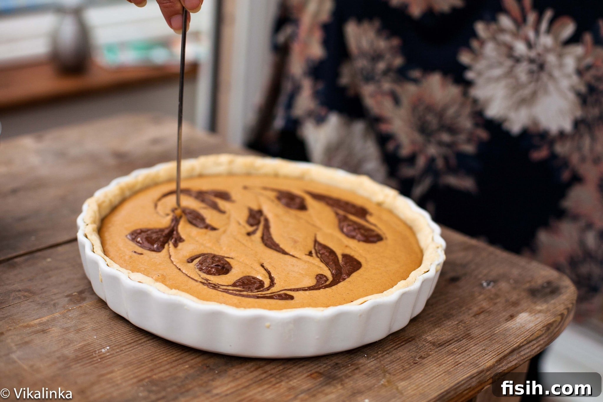 A close-up shot of a pumpkin pie filling in a crust, with swirls of melted chocolate creating a beautiful marbled effect, ready for baking.