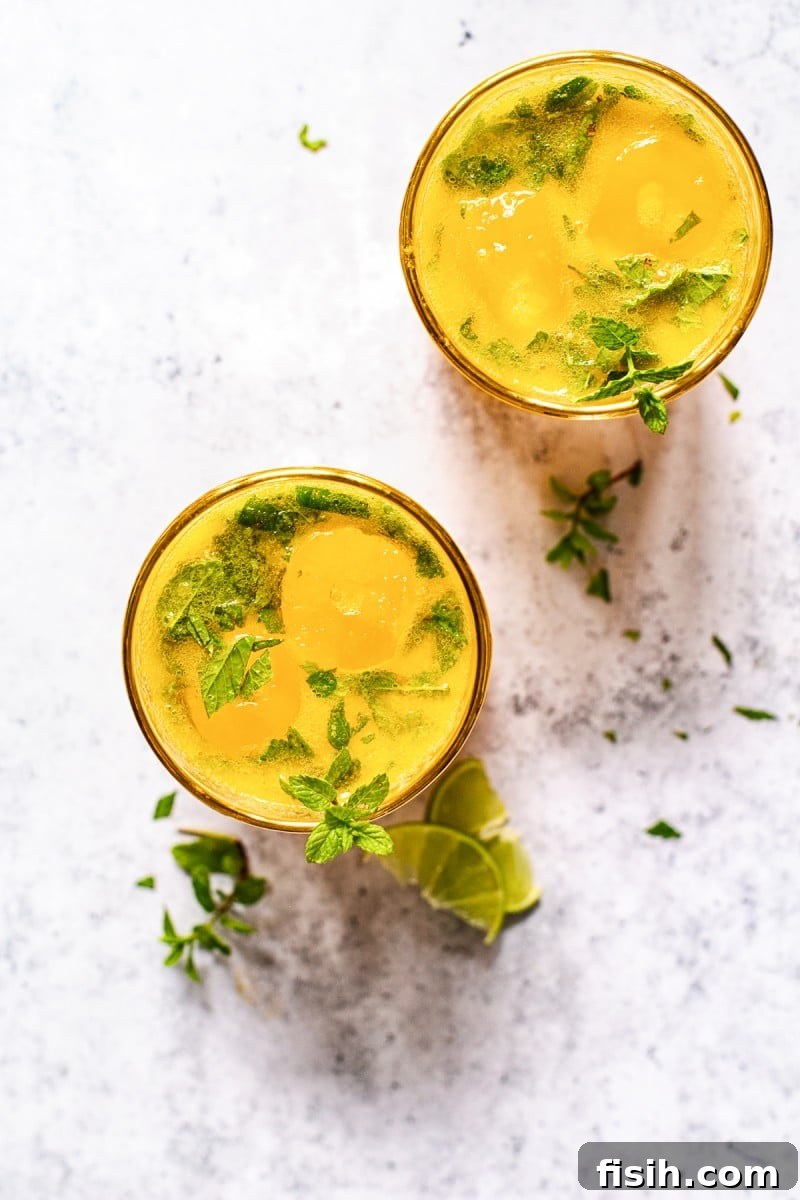 Overhead view of a prepared Mango Mojito with lime and mint garnishes.