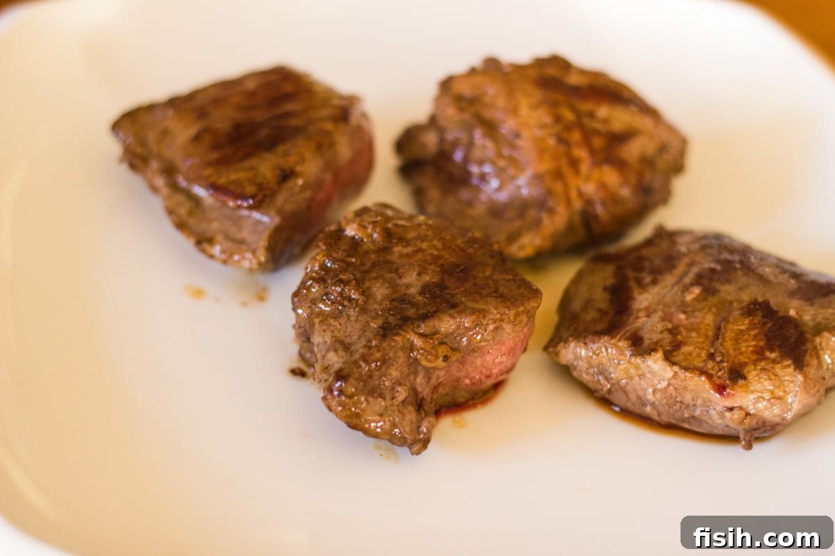 Side shot of cut browned steak on white plate