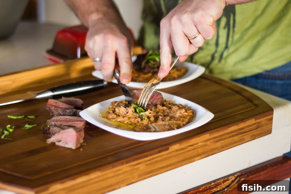 Side shot of steak being cut on wooden cutting board