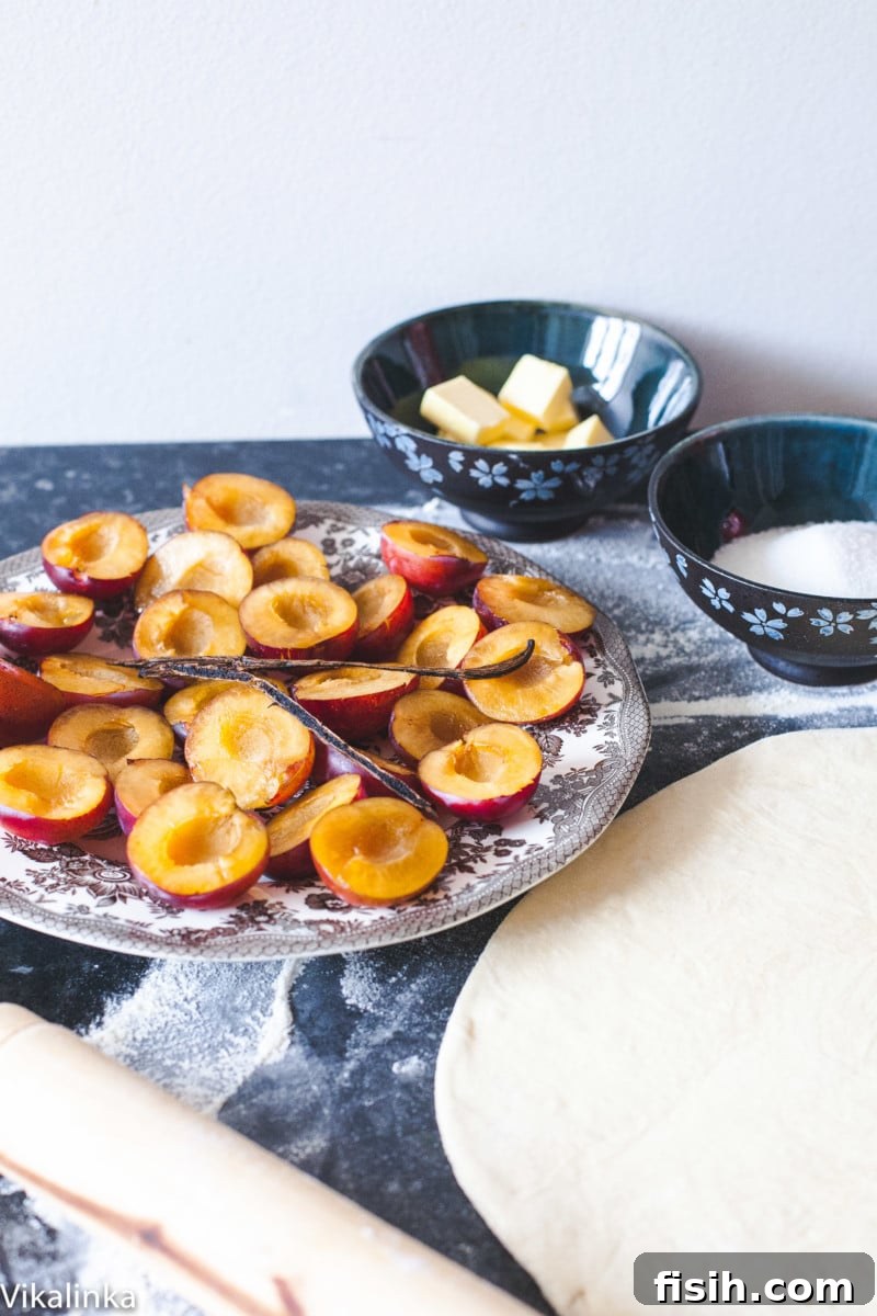 plums cut in half on plate, puff pastry rolled out and bowl of sugar and cubed butter