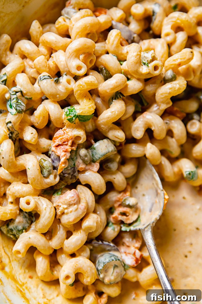 Close-up shot of creamy Mediterranean pasta with zucchini, served in a bowl with a serving spoon