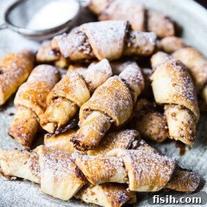 Honey-Kissed Cinnamon Walnut Rugelach 7 Rugalech on a plate with dusting of sugar
