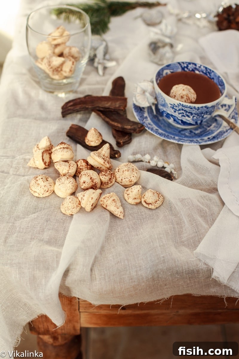Two cups of Italian Hot Chocolate garnished with meringue kisses, surrounded by whole meringues and cinnamon sticks.