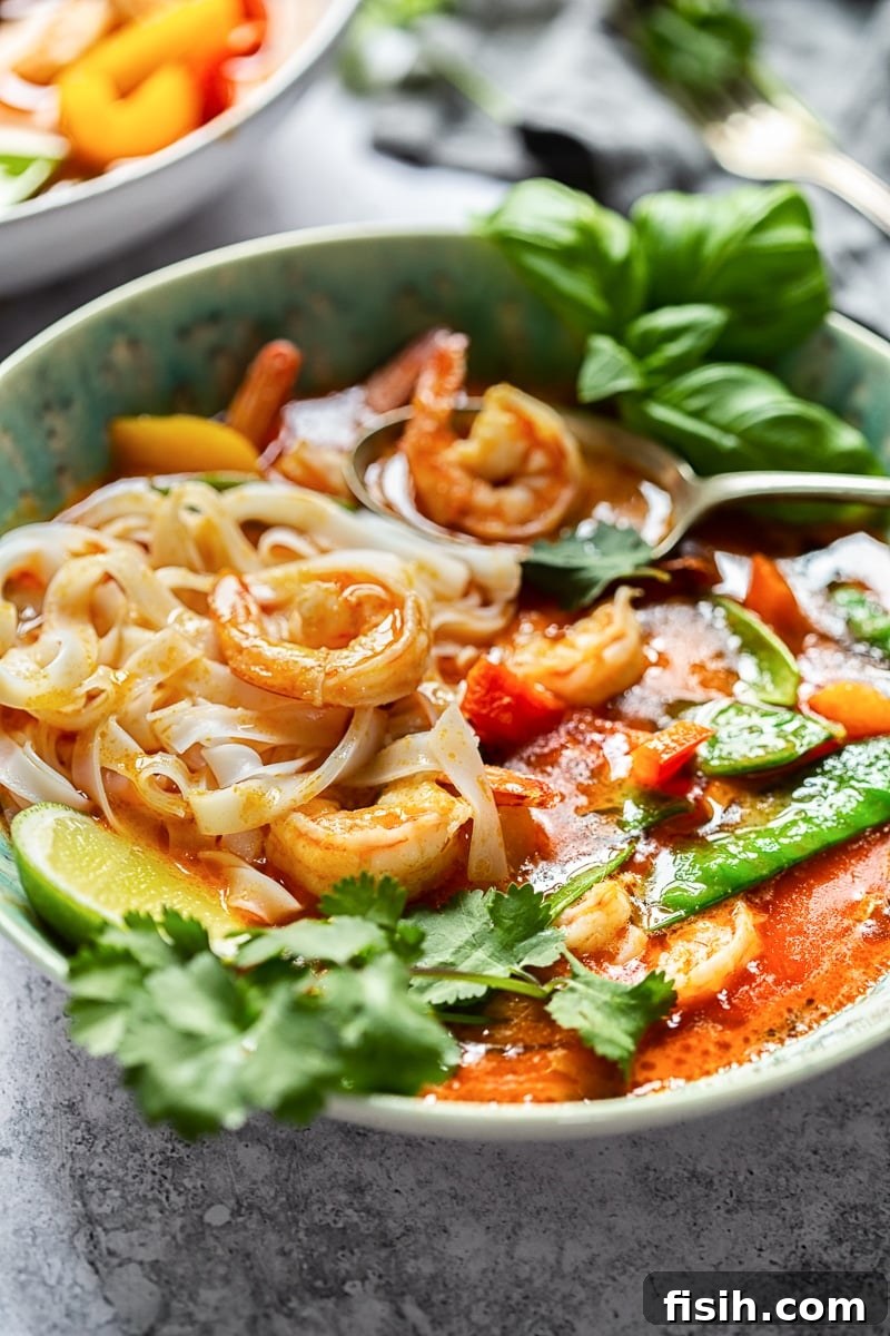 A beautifully plated Thai Red Curry with Prawns and Snow Peas in a blue bowl, garnished with fresh herbs, ready to be enjoyed.
