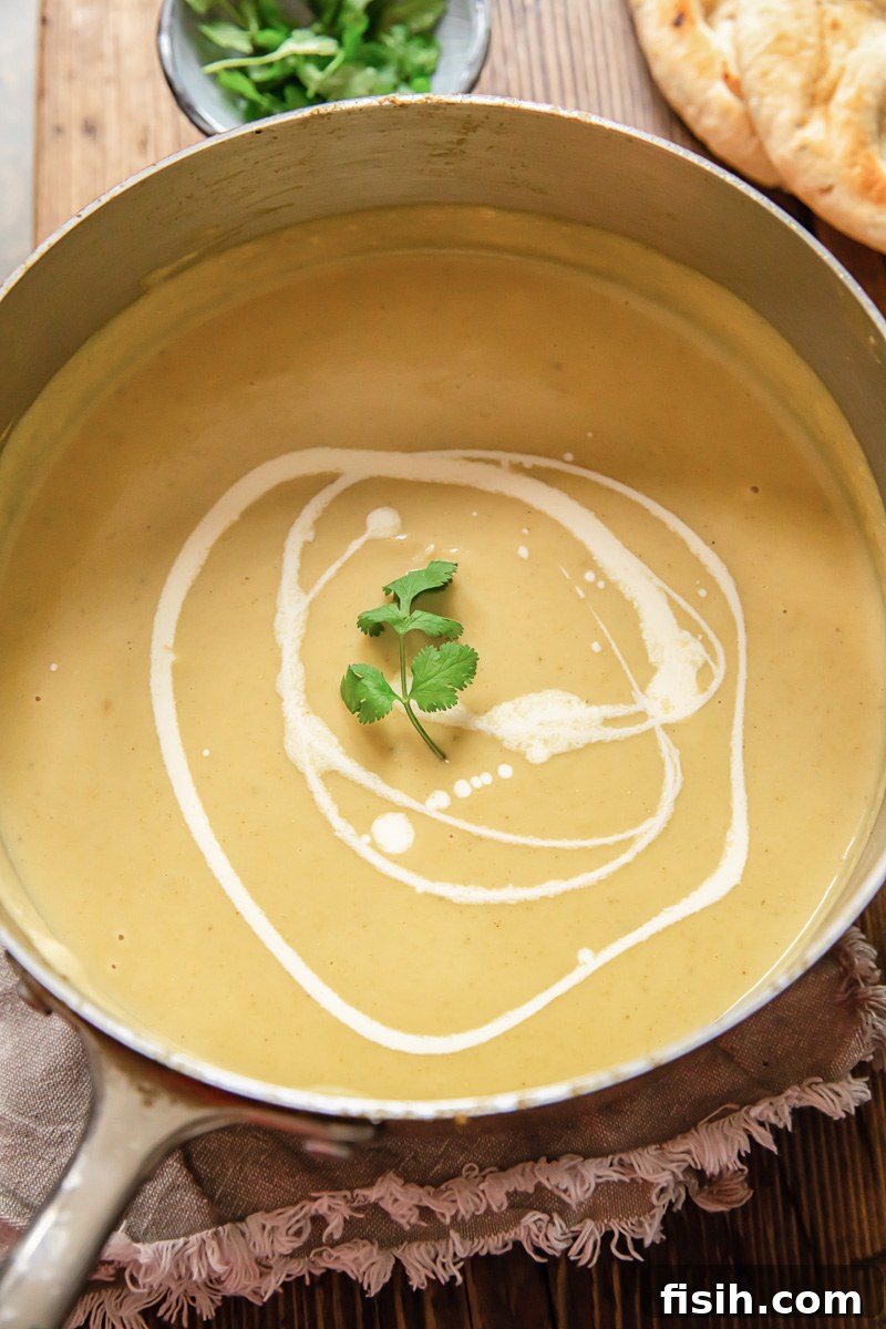 Top-down view of creamy cauliflower soup simmering gently in a large pot, ready for blending.