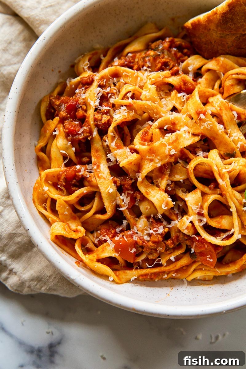 Classic Spaghetti Bolognese 4 Traditional tagliatelle pasta coated in a hearty red meat sauce, presented beautifully in a ceramic bowl.
