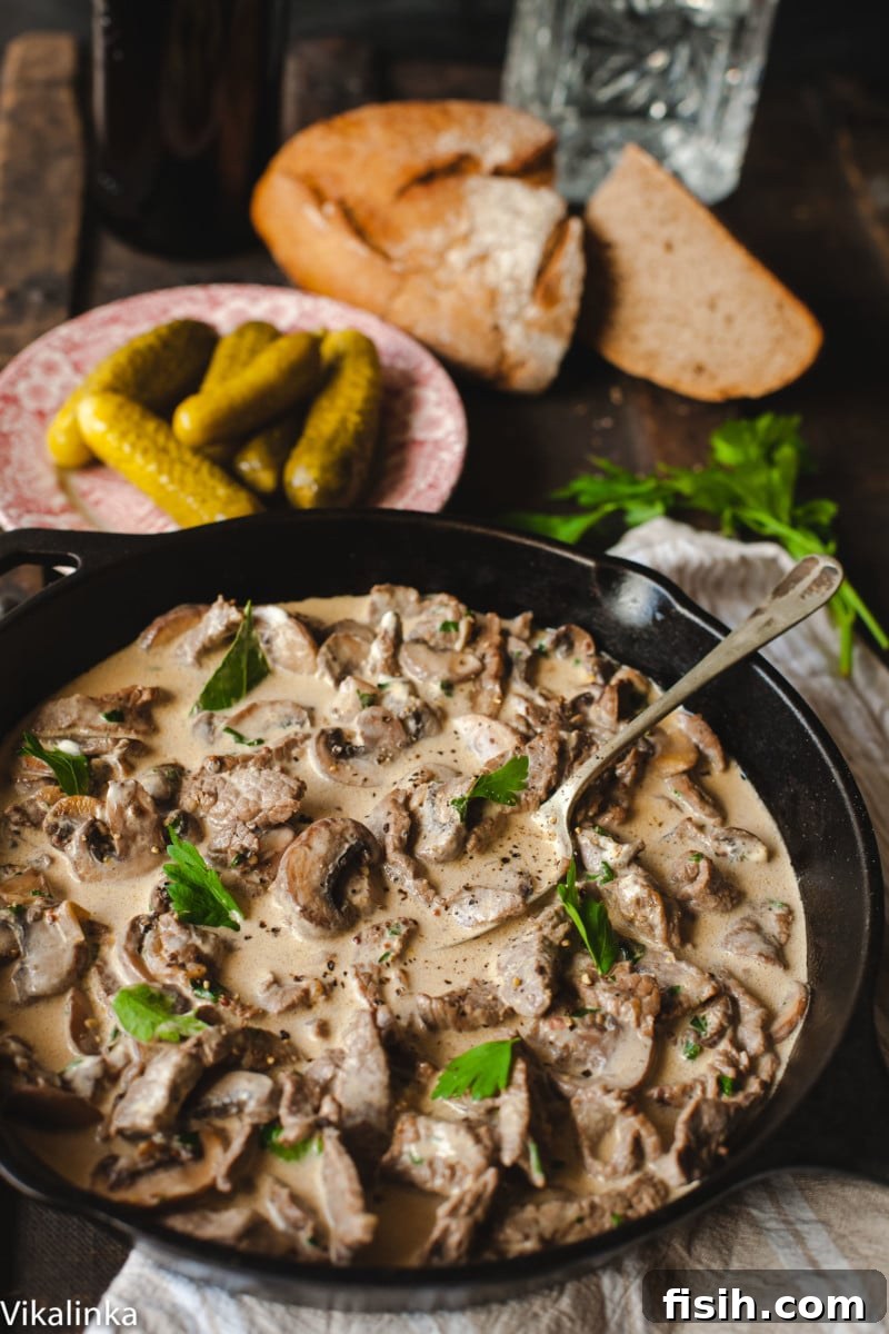Creamy meat and mushrooms with sprinkled parsley in cast iron pan