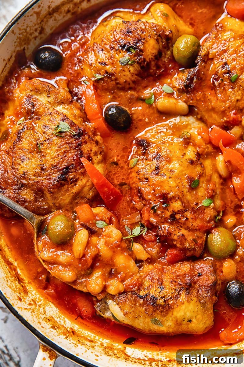 Close-up shot of Spanish chicken in a pan, showcasing the rich tomato sauce and tender chicken.