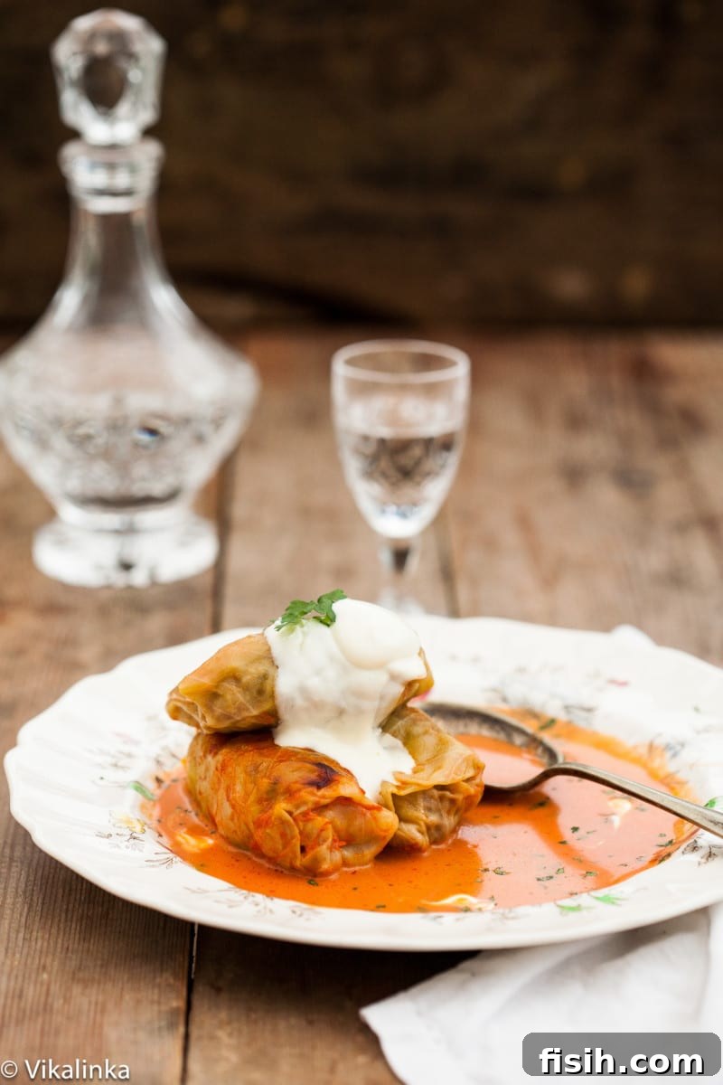 Three beautifully cooked cabbage rolls generously coated in a creamy tomato sauce, served on a white plate with a subtle background blur, ready to be enjoyed.