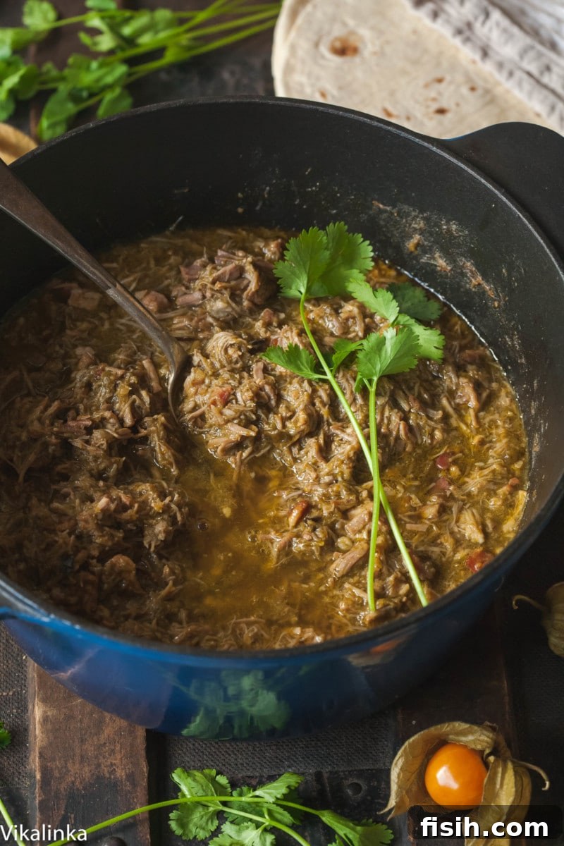 A robust green chili stew bubbling gently in a blue Dutch oven on the stove, radiating warmth and rich aroma.