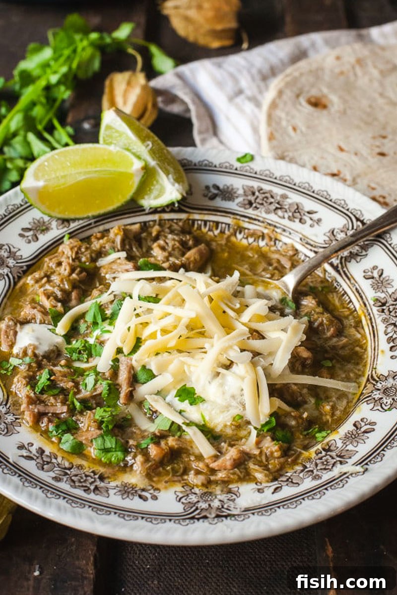 A delectable bowl of Chili Verde, generously topped with a sprinkle of grated cheese and fresh chopped cilantro, ready to be enjoyed.