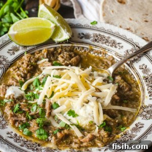Chili Verde in a bowl topped with grated cheese and chopped cilantro