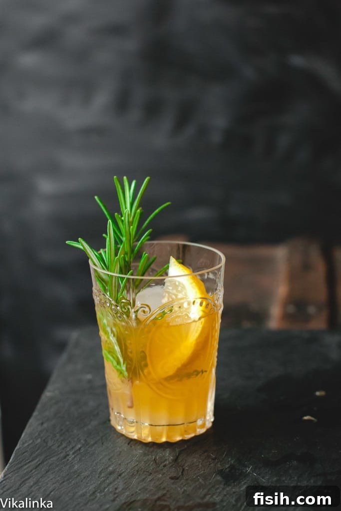 Cognac Zest 2 A beautifully crafted Cognac Sour cocktail, garnished with a lemon wedge and a rosemary sprig, on a dark background.