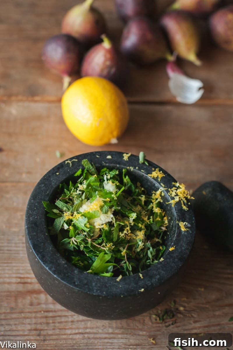 Chopped fresh herbs and lemon zest in a mortar and pestle, ready to be combined for a turkey rub