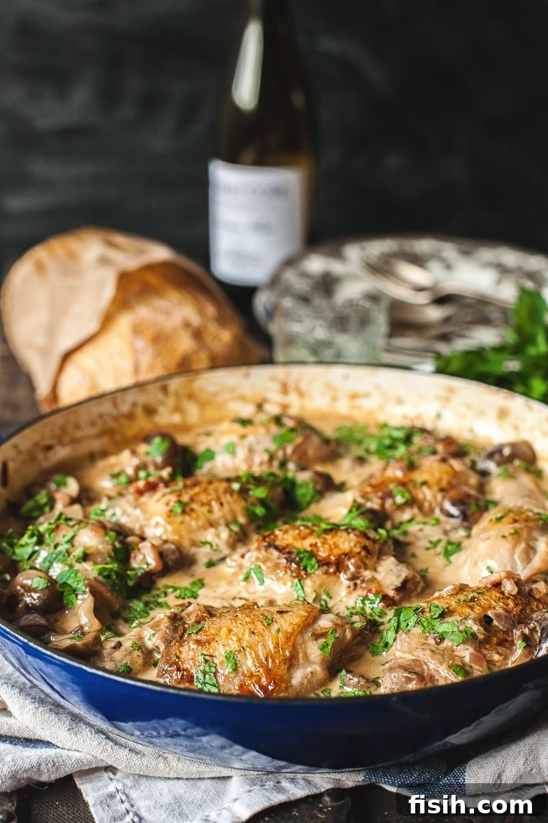 White Wine Braised Chicken 2 Coq au Chardonnay in a pan with bread in the background, showcasing a rustic French meal