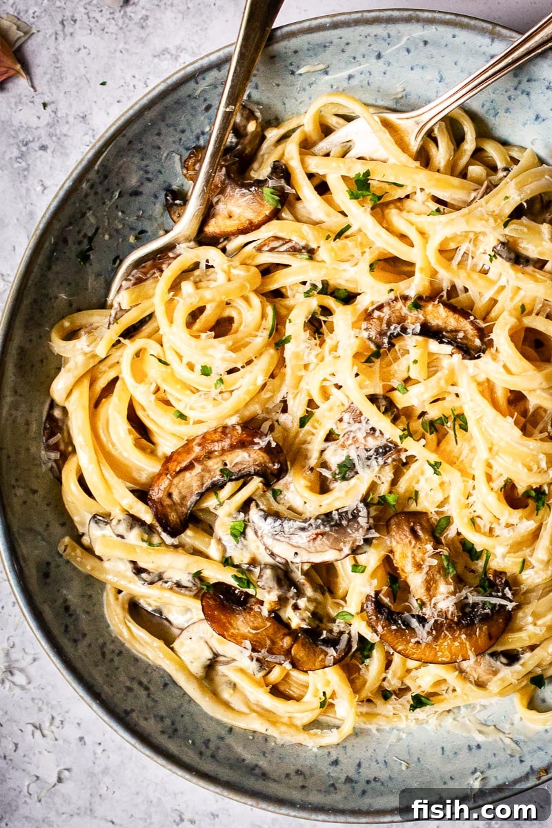 Rich Truffle Cream Tagliatelle with Crispy Bacon and Forest Mushrooms 2 Creamy tagliatelle with mushrooms and bacon in a blue bowl with two forks in, ready for a romantic dinner.