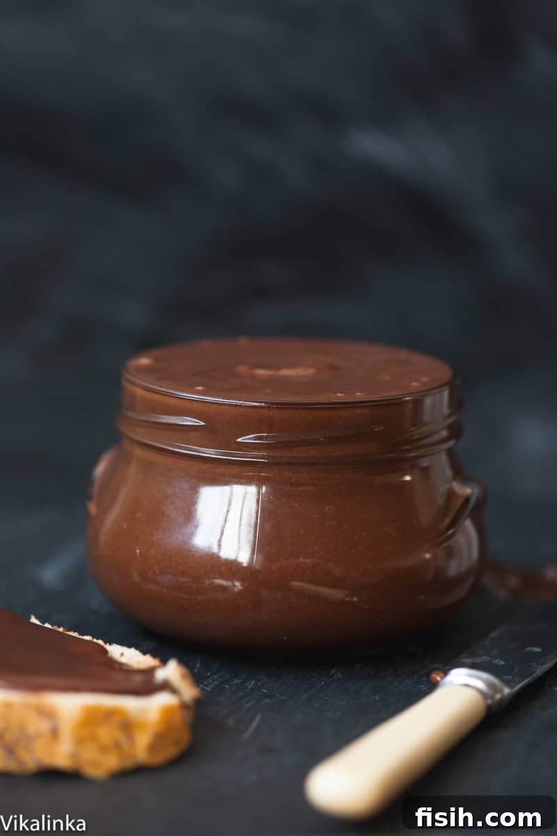 Side shot of homemade chocolate almond butter in a glass jar, showcasing its smooth, rich texture.