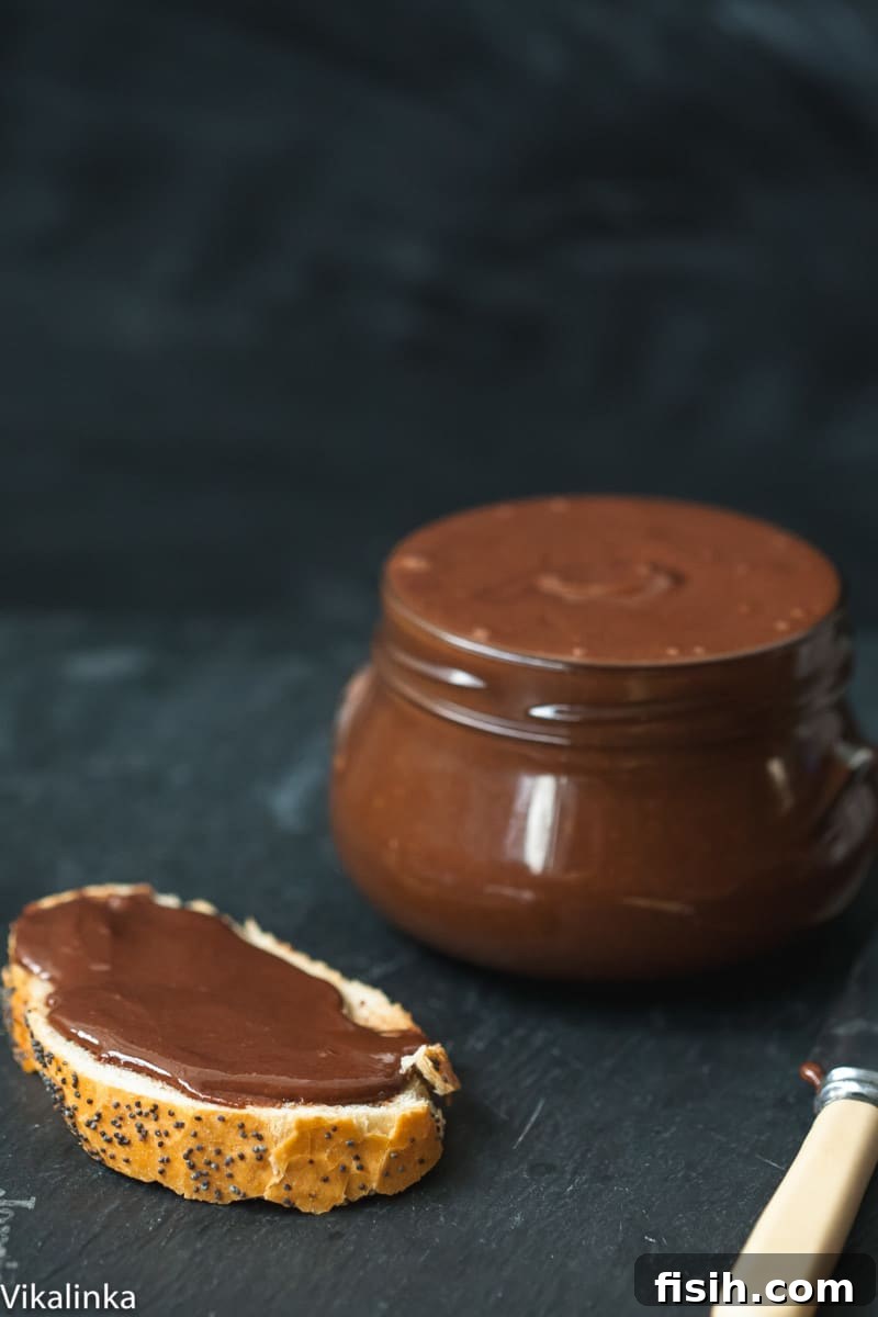 Close up of chocolate almond butter spread on bread, with a jar of the butter next to it.