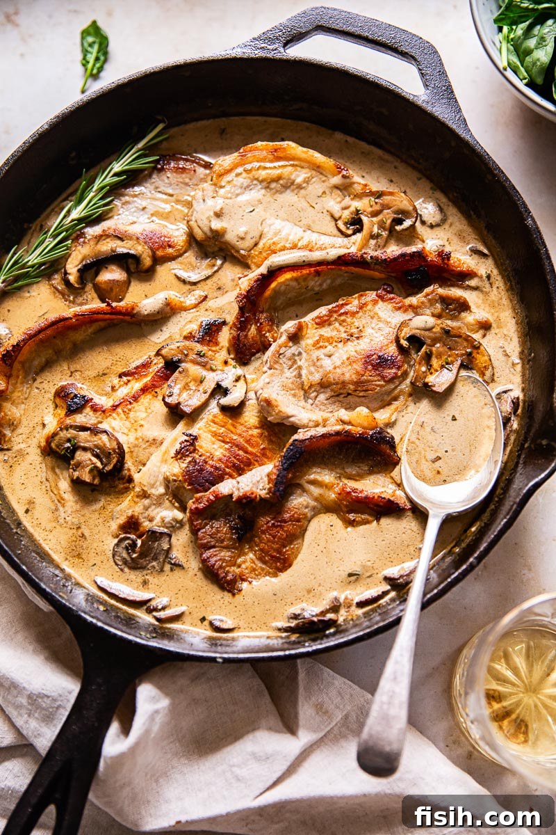 pork loin steaks in creamy sauce with mushrooms in black pan