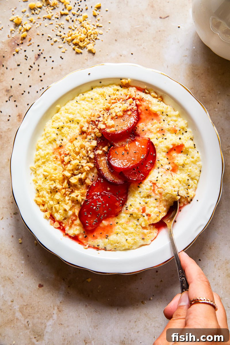 Honey-Glazed Plum & Millet Delight 5 top down view of a bowl of porridge with a hand reaching in with a spoon