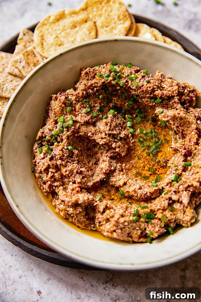 Creamy Feta Olive Tapenade 4 close up of homemade olive tapenade in a grey bowl, garnished with fresh basil