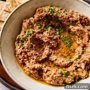 close up of tapenade in a grey bowl, garnished with fresh herbs