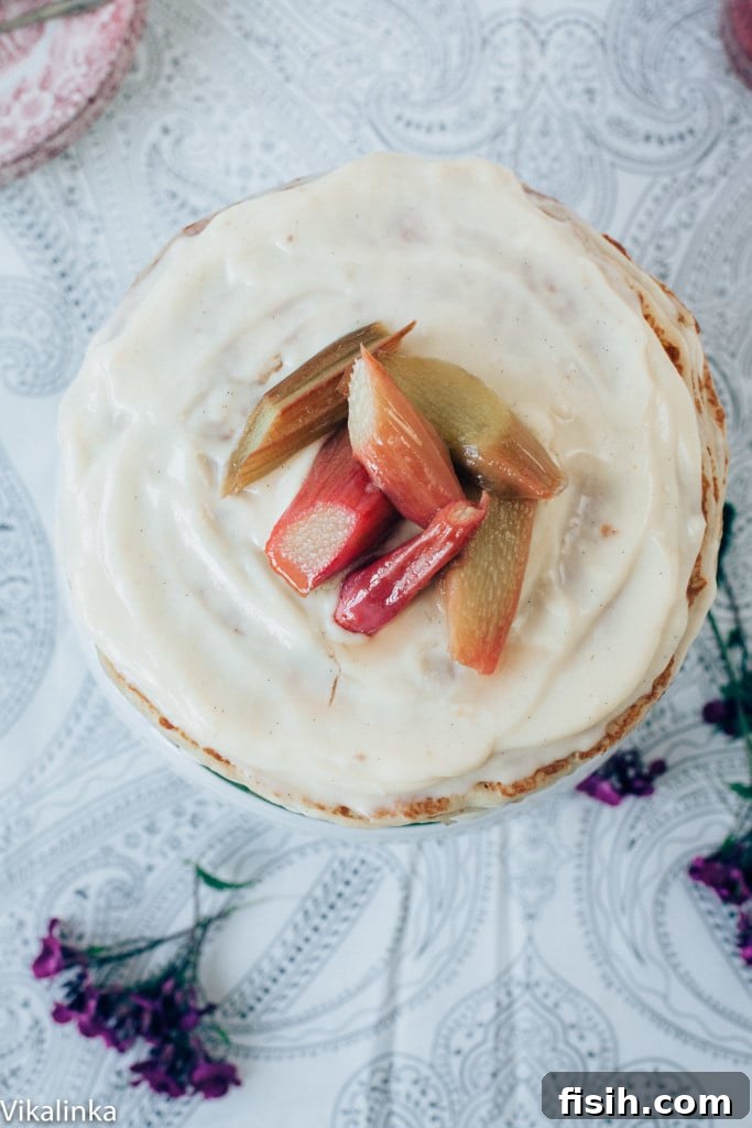 Rhubarb Custard Mille Crêpe Dream 4 Top-down view of a completed crepe cake, garnished with fresh rhubarb pieces, ready to be served.