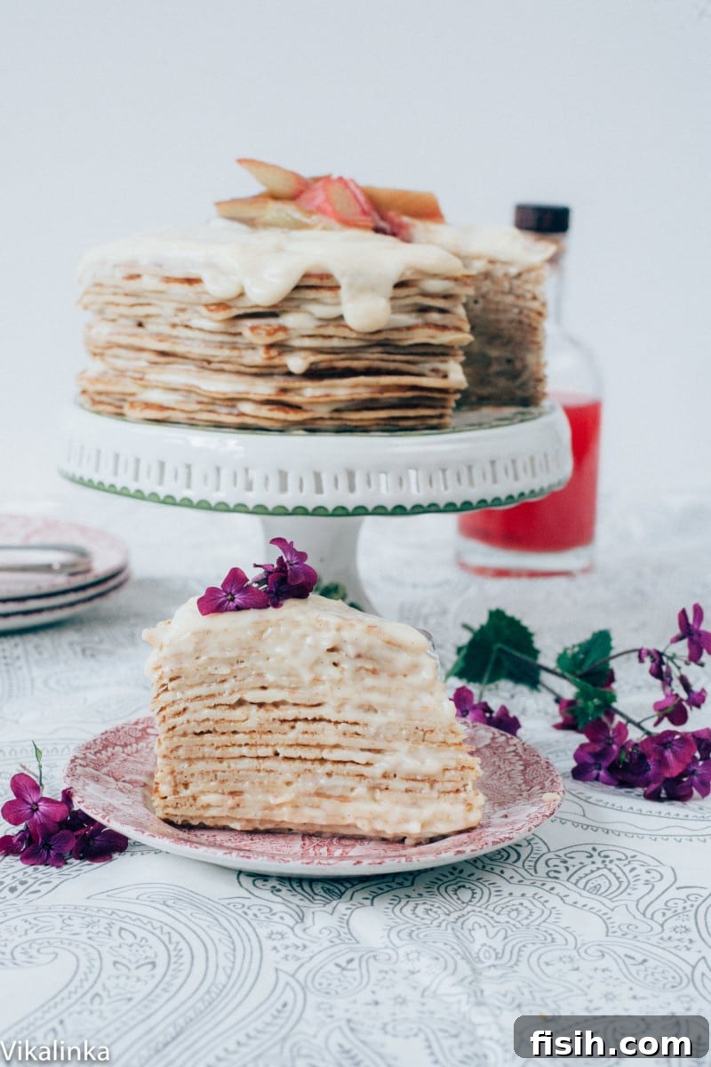 Rhubarb Custard Mille Crêpe Dream 5 A slice of rhubarb custard crepe cake on a plate, with the full cake visible in the soft-focus background.