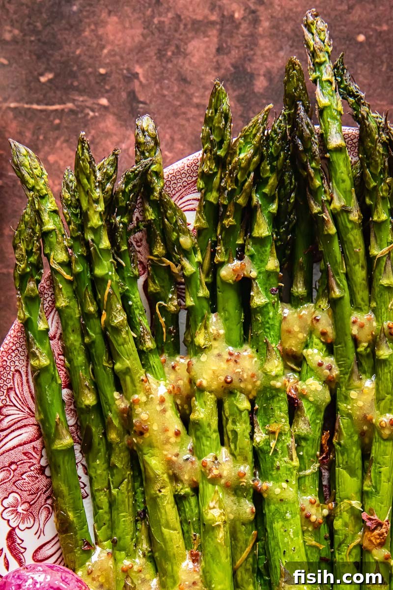 Crisp Roasted Asparagus and Radishes with Zesty Mustard Vinaigrette 3 Overhead shot of perfectly roasted asparagus spears on a serving platter, glistening with a light drizzle of mustard vinaigrette.