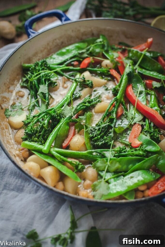 Vibrant Vegetarian Thai Green Curry with Potatoes, Snow Peas, Chickpeas, and Broccoli, served in a bowl with rice.