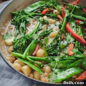 A bowl of fresh Vegetarian Thai Green Curry with New Potatoes, Snow Peas, Chickpeas, and Broccoli, garnished with fresh cilantro.