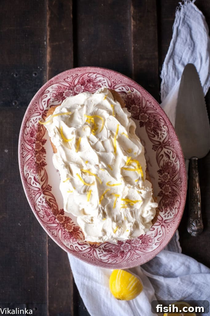Zesty Lemon Ricotta Cloud Cake with Tangy Cream Cheese Frosting 6 A delightful top-down view of a lemon ricotta cake on an elegant platter, showcasing its thick layer of creamy frosting beautifully adorned with bright lemon zest, ready for serving.