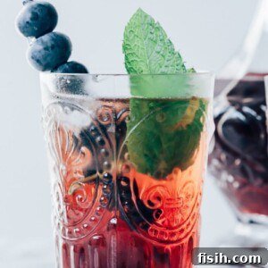 A refreshing Vermouth Cassis cocktail garnished with blueberries and mint.