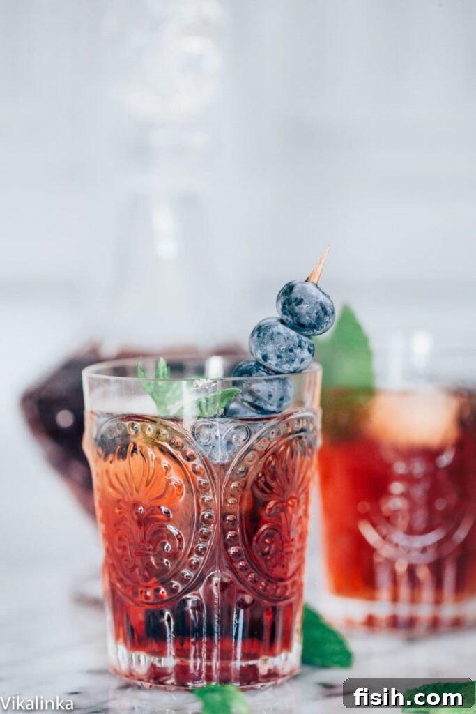 A refreshing Vermouth Cassis cocktail with blueberries and mint, perfect for a hot day.